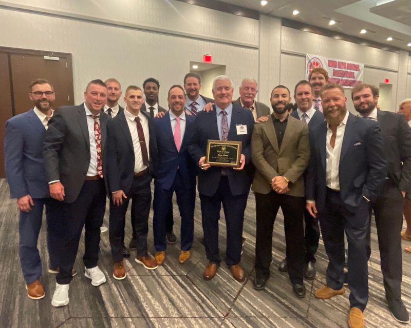 Retired boys basketball coach Dave Close, in the middle with a plaque, stands with players he coached at Stow-Munroe Falls High School during a Ohio High School Basketball Coaches Association Hall of Fame banquet in Columbus, April 25, 2026.