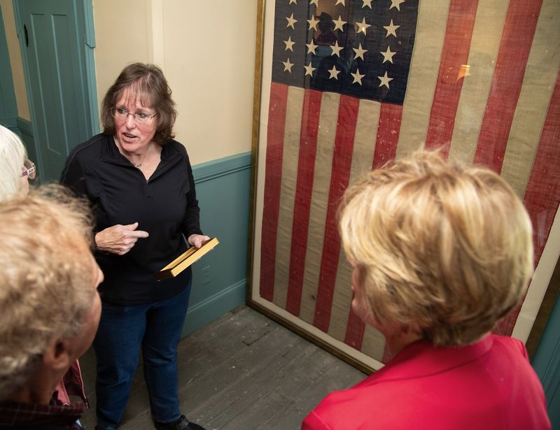 Jody (McClun) Lund, left, who donated this Civil War-era U.S. flag to the Marlboro Township Historical Society, speaks April 30, 2026, with guests during a dedication at the Dr. Kersey G. Thomas Home and Office museum in Marlboro Township.