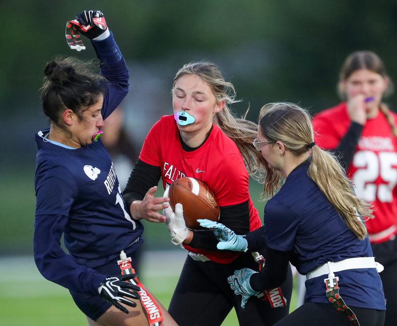 Field’s Morgan Stoicoiu, center, is stopped by Rootstown’s Cloe Bengtson, left, during the second half of a high school flag football scrimmage, May 1, 2026, in Mogadore, Ohio.