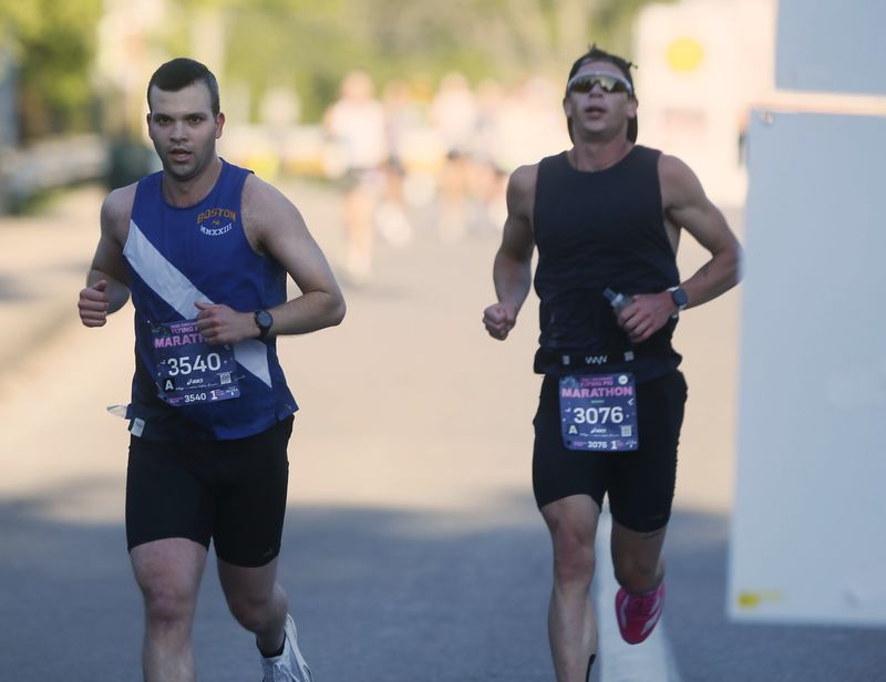 Brian Dewine, left, and Luke Birdsong pass the halfway point in Madisonville during the 2026 Flying Pig Marathon, May 3, 2026.