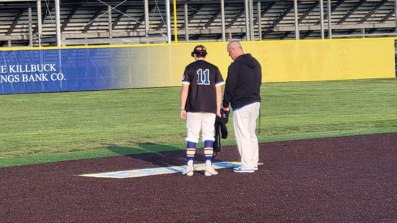 Wooster baseball player Brian Lapp (No.11) and head coach Steve Young share a moment in front of Maddox Graser's spray painting in the infield after Wooster's 7-2 home win over Lexington on Monday evening.