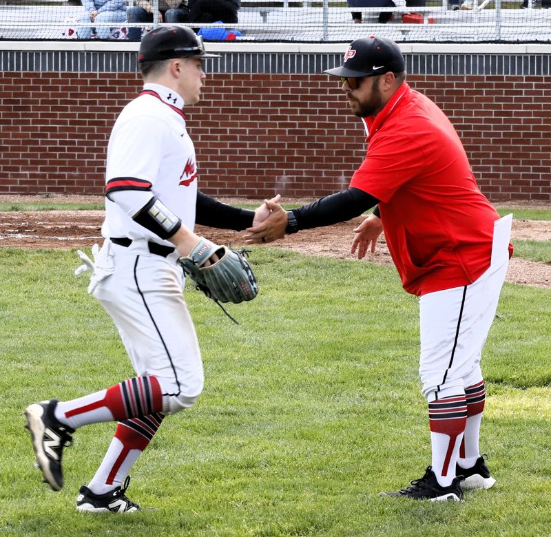 New Philadelphia's head coach Tyler Weisel gives a high five to Caleb Crowthers at the end of an inning on May 6, 2026. The Quakers defeated the Knights 5-0.