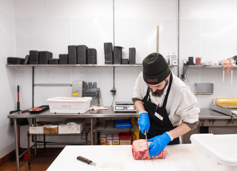 Daniel Phillips, co-owner of Weiland’s Market, cuts meat at the Clintonville grocery store.