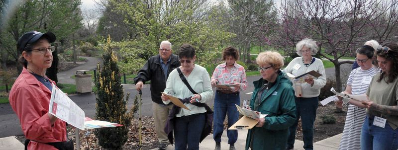 Cathy Herms is handing out a list of weeds to find on a walk through the Arboretum.