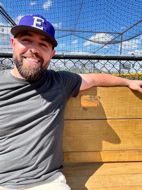 Adam Baum, former Enquirer writer and 2006 Elder graduate, sits on the bench in Elder's bullpen dedicated to him on May 11. Baum was a bullpen catcher for Elder and was with the team for its 2005 state championship.