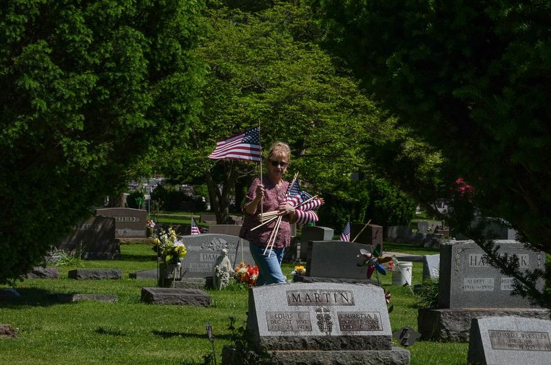Laura Cunningham walks Thursday, May 21, 2026, through Standing Rock Cemetery in Kent and places American flags on the stones of veterans who have given their lives in service to the country.