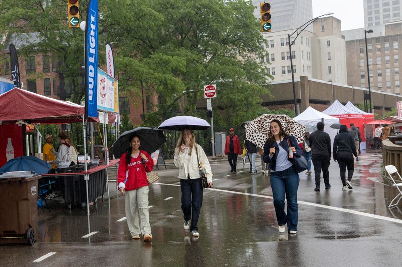 Bethany Eckman, Radhika Agrwal and Morgan Weltzer don't let a little rain stop them from enjoying the great food available at Taste 2026.