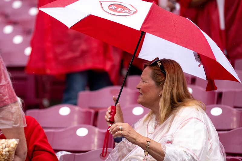 A Cincinnati Reds fan sits in the rain as the scheduled game between the St. Louis Cardinals and Cincinnati Reds at Great American Ball Park in Cincinnati on Sunday, May 24, 2026 is canceled due to weather.
