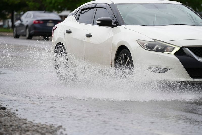 Cars drive through a puddle on Harrisburg Pike on the southwest side of Columbus after heavy rains on May 27, 2026.
