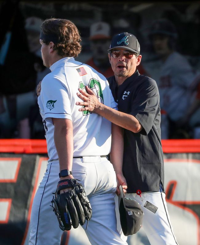 Aurora baseball coach Glenn Galang comforts pitcher Drew Scott as he comes off the field between innings during a Division III district baseball game, May 28, 2026, in Massillon, Ohio.