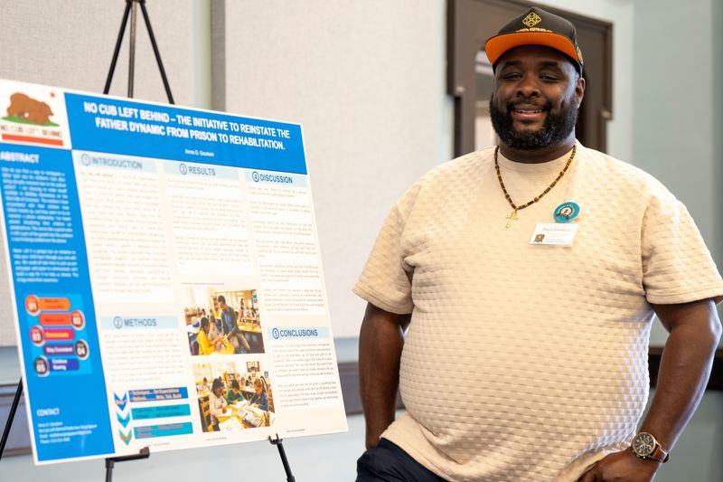 Amos Goodwin poses in front of a presentation he made during a graduation for fathers from a Cincinnati Parent Empowerment Network program in East Price Hill on Sunday, May 31.