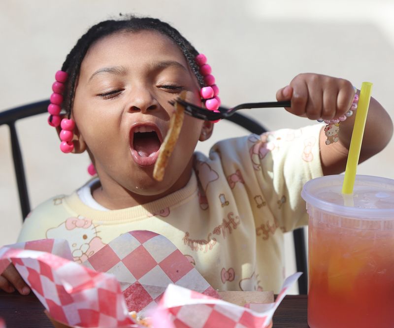 Kaliyah Partridge, 4, of Massillon, eats fresh cut fries at the Spring Spirit Bizarre hosted by Lotus Grove Wellness in downtown Massillon. Saturday, May 30, 2026.