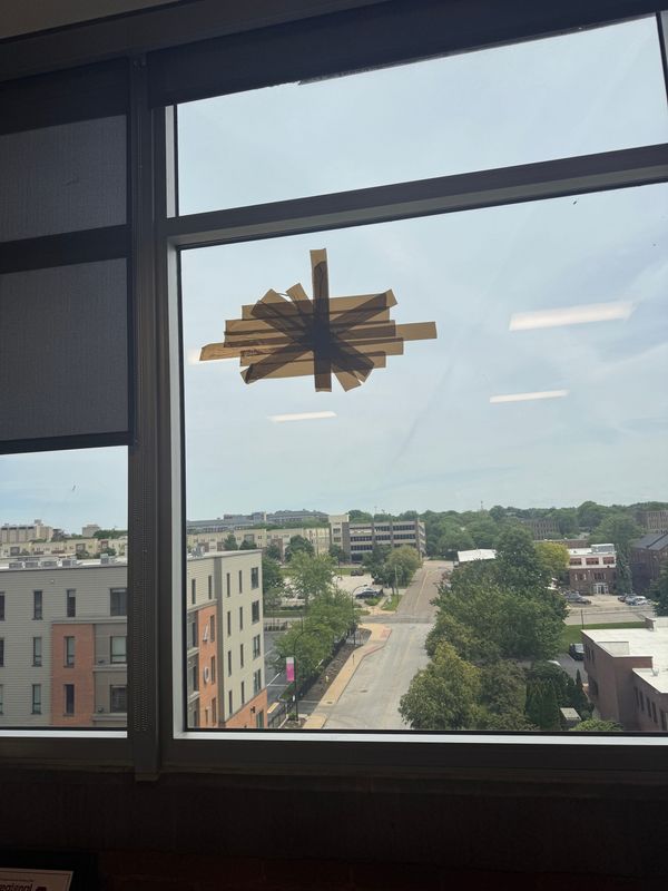An asterisk of tape temporarily covers a bullet hole and splintered glass in Executive Editor Cheryl Powell's office at the Akron Beacon Journal.