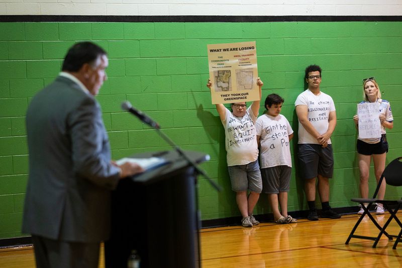 A small group silently protest Mayor Andrew Ginther’s press conference announcing ,details of the Southwest Columbus Community Plan.The group is in opposition to the city’s backroom deal handing McCoy Park over to the Haslam Sports Group.