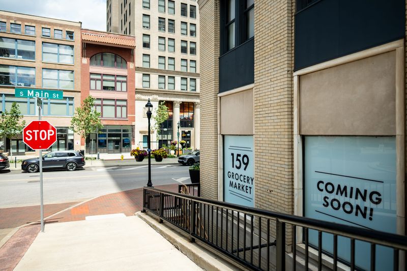 Signage announcing the forthcoming buildout of 159 Grocery Market, located in the 159 Main building at the corner of South Main Street and Church Street in downtown Akron recently popped up on the heels of announcement of another small grocer, The Mercantile, at 1 Cascade Plaza.