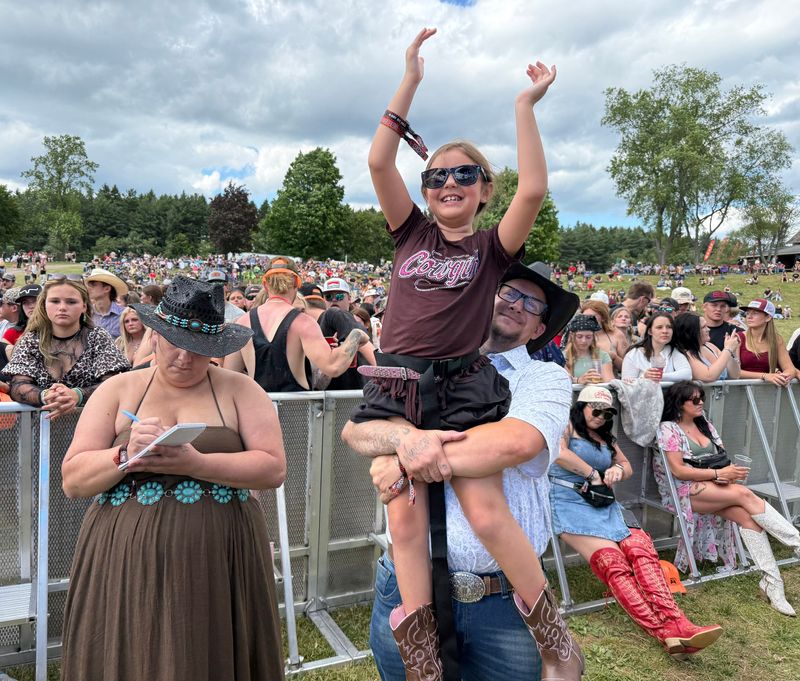 Chris Kelly, 40, of Atlanta holds his stepdaughter, Hannah Boyd, 8, during The Country Fest on June 18 at Clay's Resort Jellystone Park in Stark County. At left is Hannah's mother, Tasha Thatcher, 34, also of Atlanta.