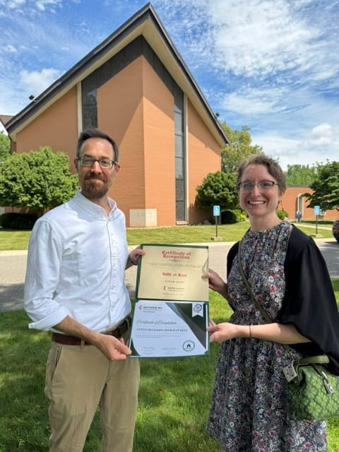 The Rev. Nathan Howe of Kent’s United Methodist Church and Claire Bank, a church member and chair of its Green Team, show off the Ohio Episcopal Area’s “Green Church Movement” certificate after a brief ceremony marking the church’s work to move to solar energy.