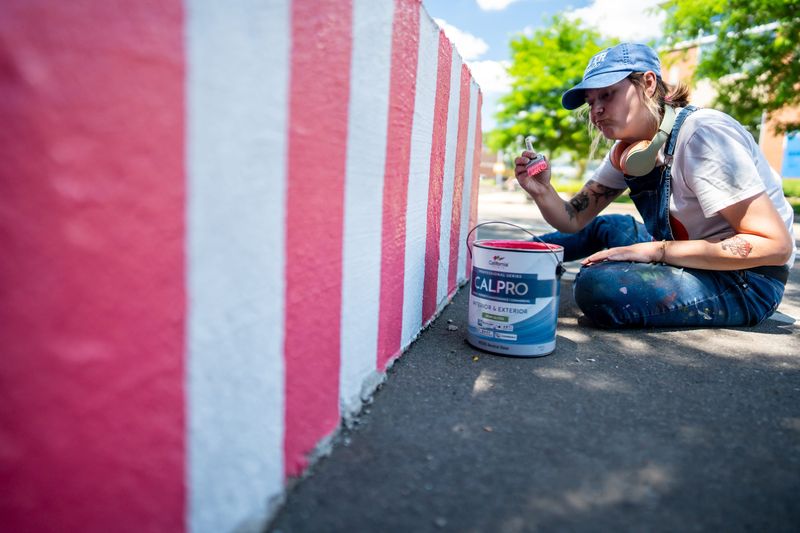 Highland Square resident and artist, Melissa McClellan, works on a series of murals she was commissioned to paint on the 16 concrete blocks, June 24, 2026, along West Market Street in Akron’s Highland Square neighborhood.
