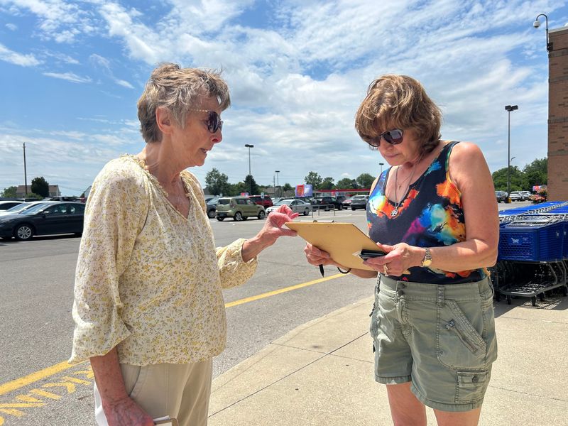 Jean W., left, offers instructions to Terry Wade, right, as she signs a petition for a constitutional amendment that would block most data centers in Ohio on June 25 in near East Broad Street Kroger in Pataskala. Jean W. was collecting signatures for both the constitutional amendment as well as a Pataskala charter amendment to prohibit construction of data centers.