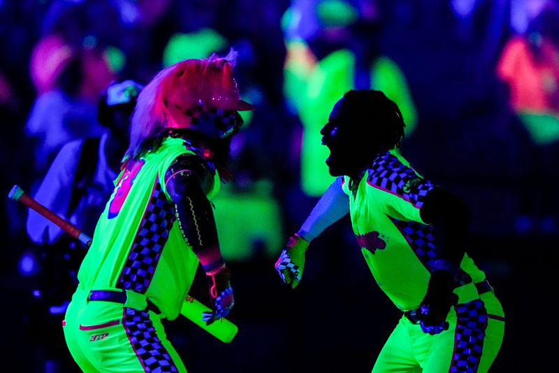 Players from the Glow Mojis celebrate a run during game 3 of the Cosmic Baseball Takeover Tour between the Cosmic Chili Peppers and the Glow Mojis, June 27, 2026, at 7 11 Credit Union Park in Akron, Ohio.