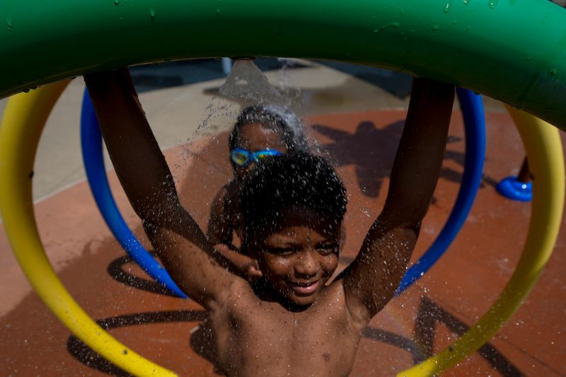 Neo Johnson, 8, of Roselawn, does a pull up on a sprinkler in the splash pad at the Pleasant Ridge Community Center in the Pleasant Ridge neighborhood of Cincinnati on Monday, June 29, 2026.