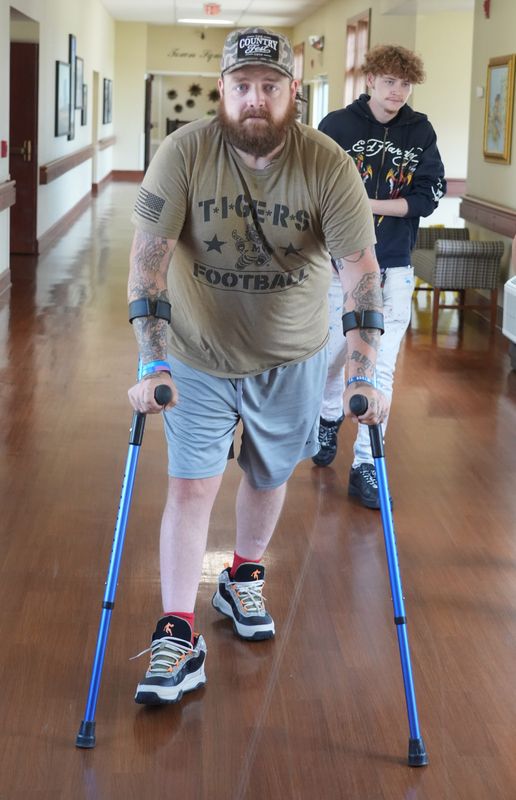 Austin Walkup, 32, walks with crutches at Sprenger Health Care Rose Lane Nursing and Rehabilitation in Jackson Township. Walkup was seriously injured in June 2024 when a tree fell on him. Doctors were not sure if he would survive.