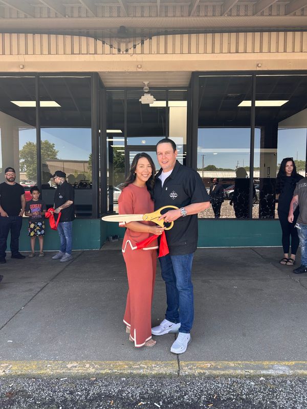 Justin Bell and his wife, Leah, pose after cutting the ribbon June 3, 2026, at his new barber college in Akron.