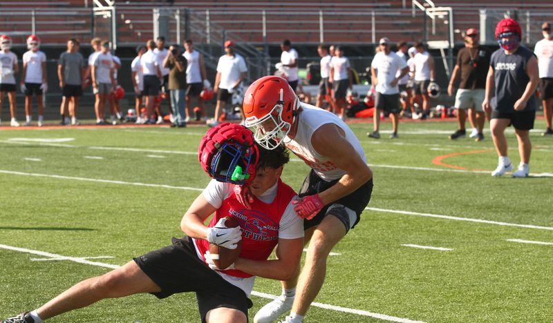 Licking Valley's Damian Rudasill holds onto a pass despite losing his helmet against Heath's Tyler Marks during a passing scrimmage at Swank Field on July 13, 2026.