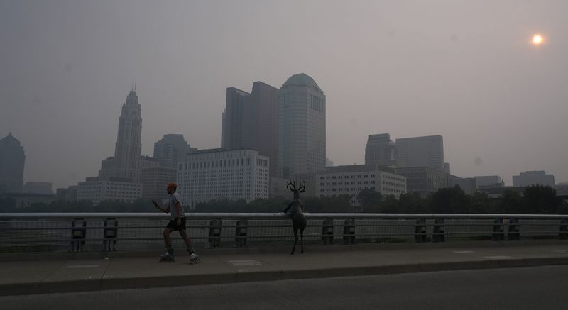 A roller-blader moves across the Town St. Bridge early Friday morning July 17, 2026 as Canadian wildfire smoke blankets the city.
