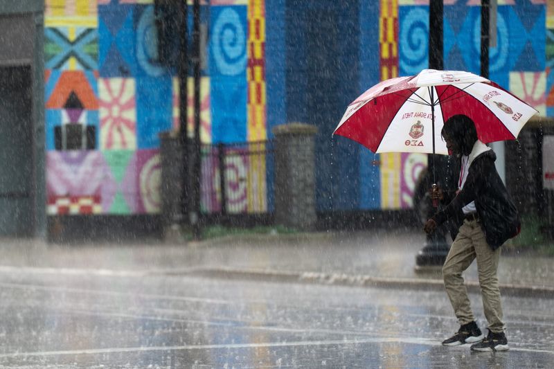 Pedestrians walk through the rain in downtown Cincinnati during a thunderstorm in Tuesday, July 21, 2026.