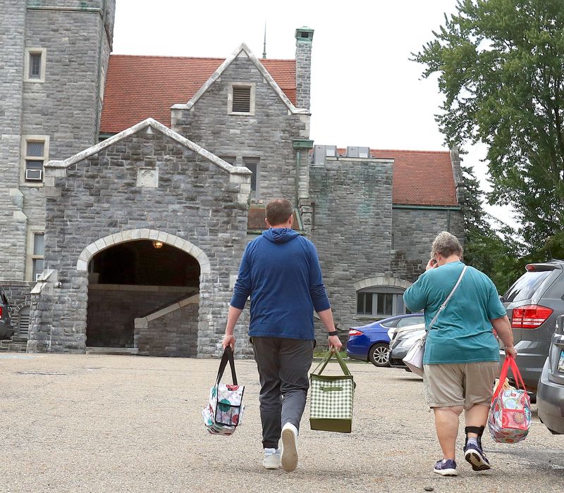 Taylor Logothetides, left, assistant principal of Alliance Middle School, carries groceries to the car of a customer at the Akron-Canton Regional Foodbank's Pop-Up event Wednesday, July 22, 2026, in the parking lot of Glamorgan Castle in Alliance.