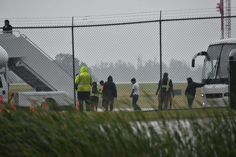 Detainees with their hands bound leave an unmarked white bus at the AVFlight facility at Akron-Canton Airport July 21 and board an Eastern Air jet bearing the tail number N668CP. (Photos taken from North Airport Road through a chainlink fence.)
