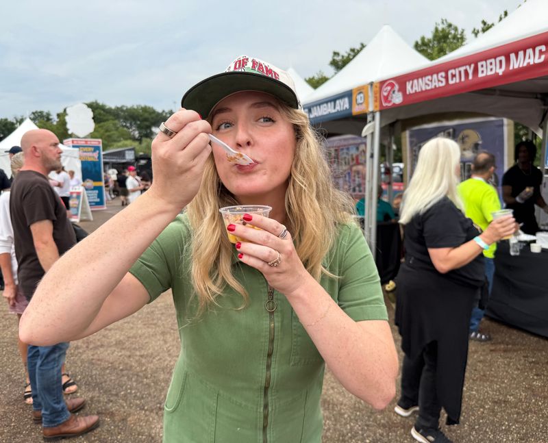 Taylor Elder, digital media strategist at the Pro Football Hall of Fame, enjoys a mac and cheese sample on Aug. 5 at the USA Today Great American Tailgate, part of the Pro Football Hall of Fame Enshrinement Festival, which continues through Aug. 9 in Canton.