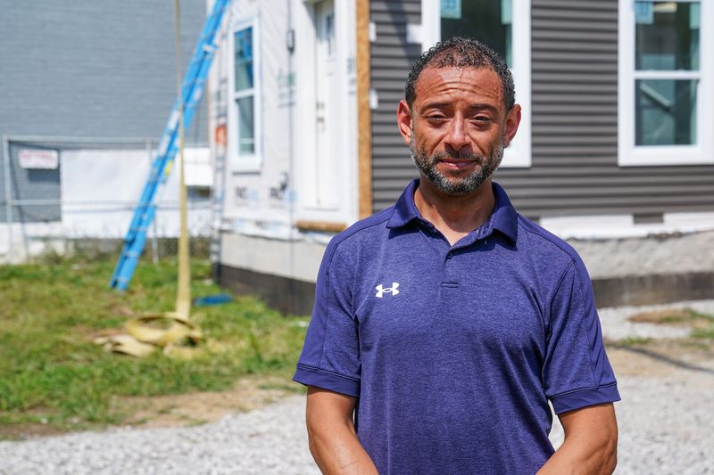 Brandon Holmes, director of neighborhood services, poses for a portrait in front of installed modular homes on the 300 block of Pleasant Street, Thursday, Aug. 6, 2026, in Covington, Ky.