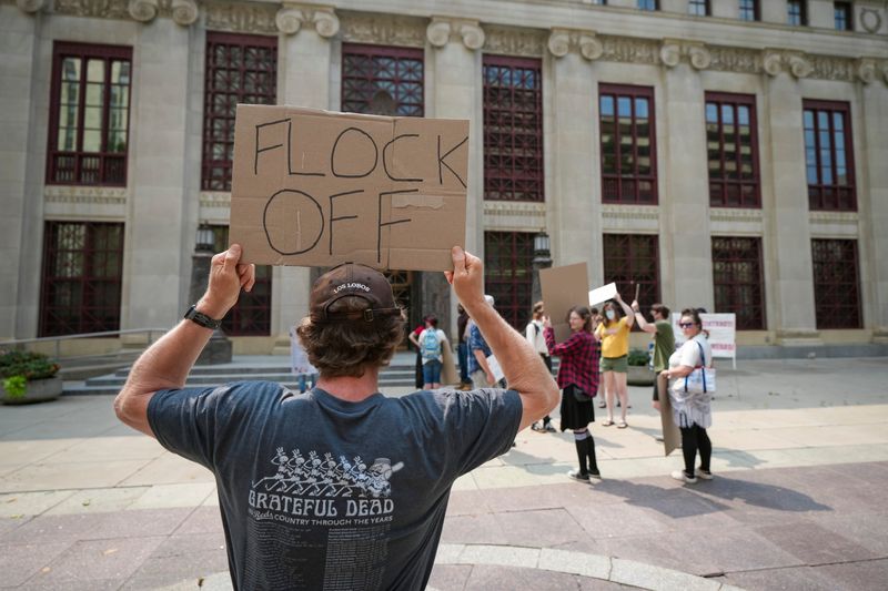 Anti-Flock surveillance protesters, including Kristopher Weiss, front, gather outside Columbus City Hall before Councilmember Emmanuel Remy holds a council hearing on the city's Flock Safety license plate reading cameras on Aug. 10, 2026.