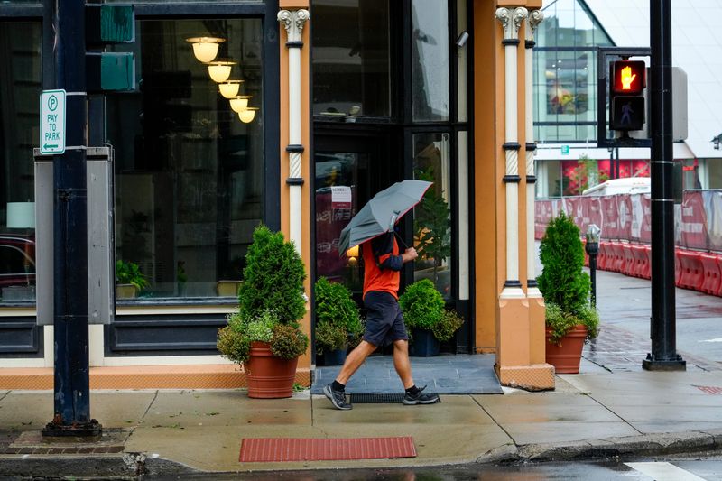 A Cincinnati pedestrian walks in the rain in the downtown area on Wednesday, Aug. 12, 2026.