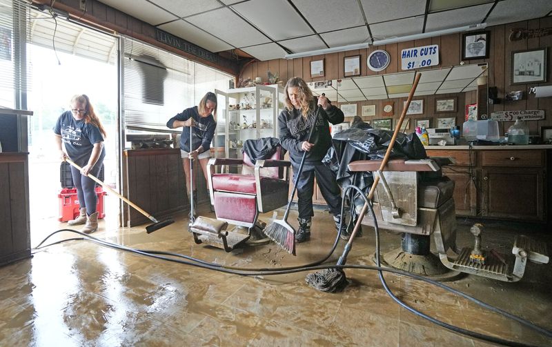 Sierra McClellan (left), Erica Atkinson (center) and Christina Fiedler remove water and mud from Jim's Barber Shop, 34 W. Main St. in Crooksville, as clean up continues Wednesday, Aug. 12, 2026, after flooding the day before caused extensive damage in the Perry County community. Ohio Gov. Mike DeWine declared Perry County one of three disaster declaration counties and called out the Ohio National Guard to assist.