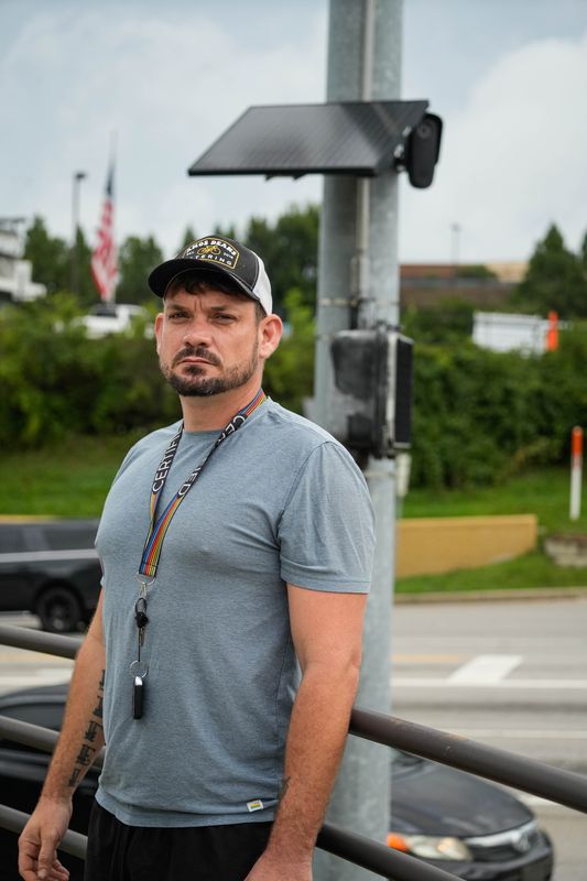 Keith Johnson stands by a Flock camera at the intersection of Rybolt Road and Harrison Avenue, down the road from his home.