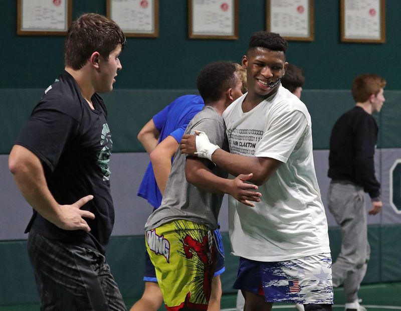 Tyler Lillard, facing, hugs assistant coach Josh Decatur after working with him during practice at Aurora High School in 2022.