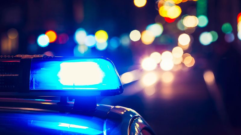 A stock image of a police cruiser with its emergency lights on at night.