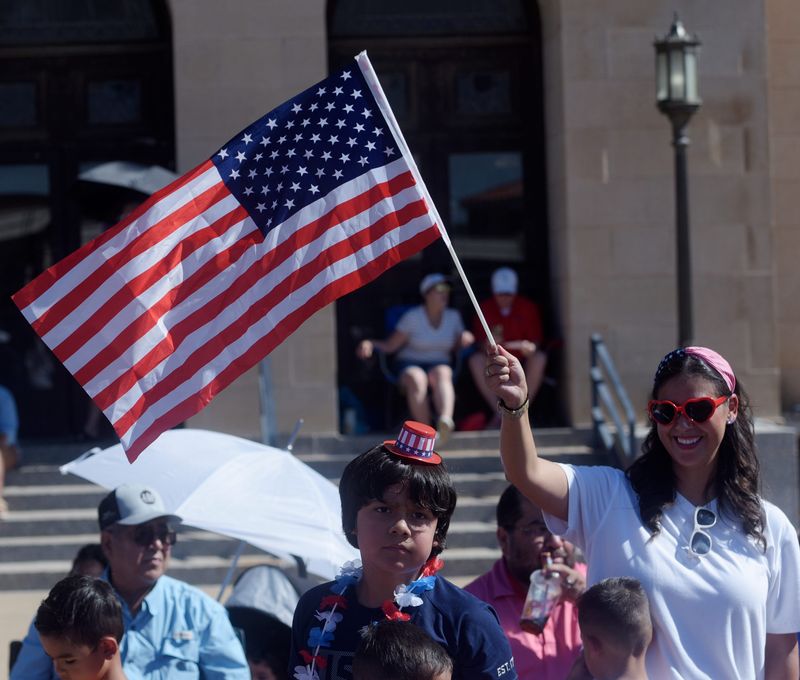 Michelle Peña waves the American flag during the 4th on Broadway Fourth of July parade, Tuesday, July 4, 2023.