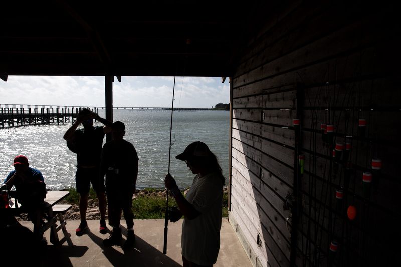 In this 2023 file photo, Emily Bauknight, an activity leader, holds up a fishing rod and explains how to use it to campers at Camp Aranzazu in Rockport.