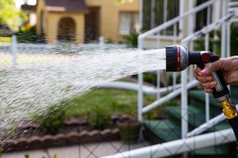 In this 2023 file photo, Pauline Garza, 91, uses a hose and shut-off nozzle to water her lawn in Corpus Christi. Stage 1 water restrictions were in effect at the time.