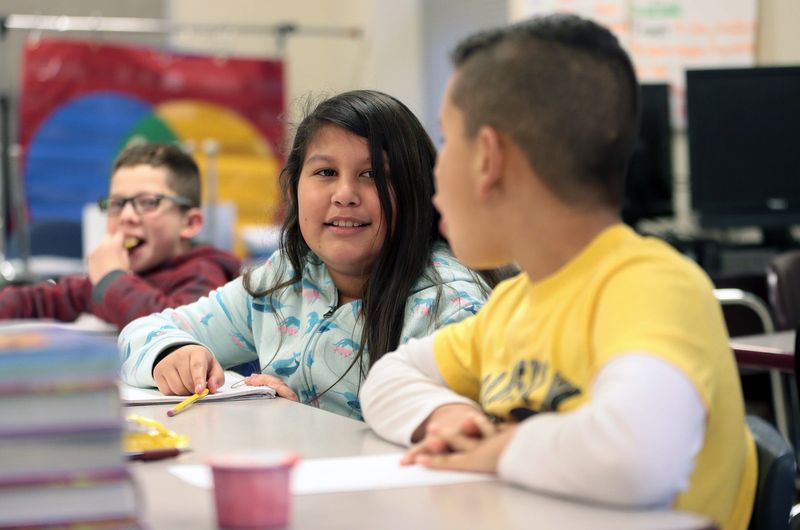 Julie talks with her deskmate in her fourth grade classroom at Columbus Elementary School.