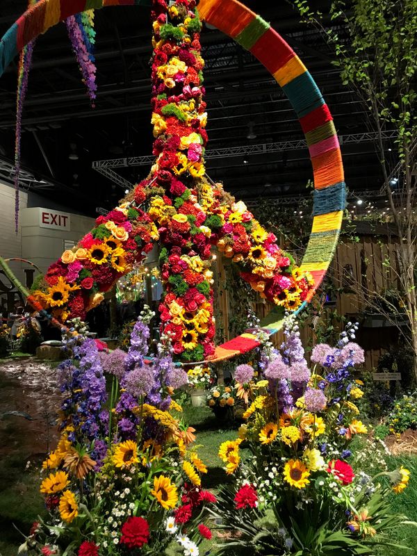 The Robertson's Flowers Woodstock-themed display at the 2019 Philadelphia Flower Show ends with a yarn-wrapped, flower trimmed peace symbol.
