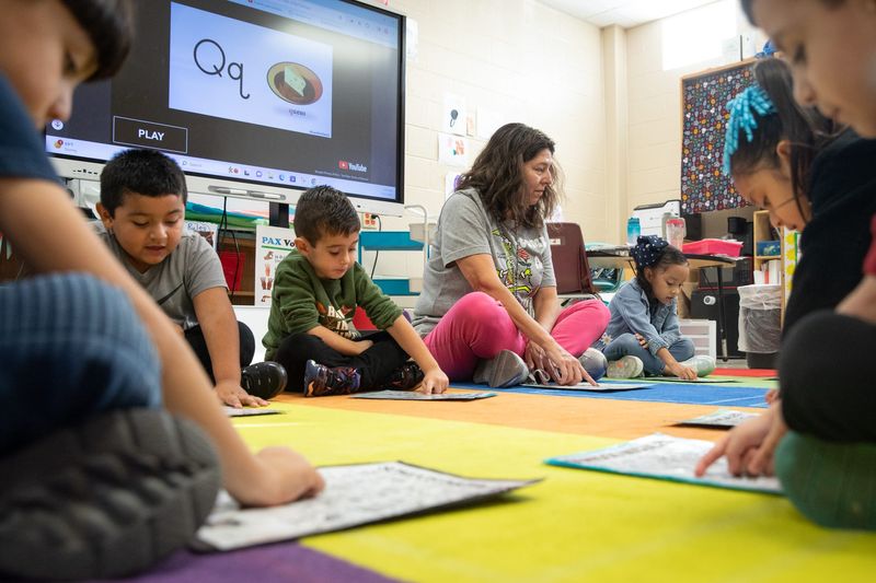 From center left, Mario Castro, Andres Villaseñor Diaz, teacher Elizabeth Barger and Sofia Briones practice the Spanish alphabet during class on Dec. 8 2023, in Corpus Christi, Texas.