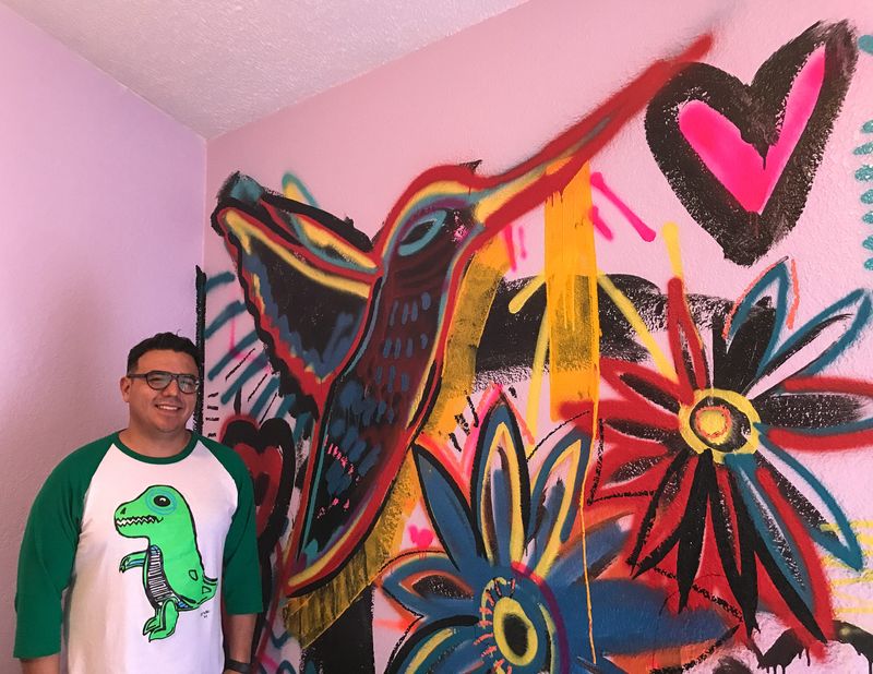 El Paso artist Diego "Robot" Martinez on Tuesday, April 13, 2021, stands by a hummingbird mural he is painting at the Child Crisis Center of El Paso.