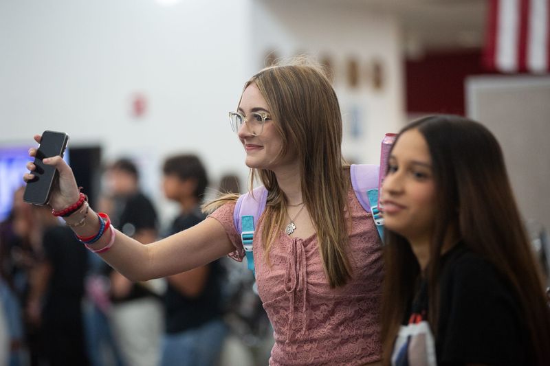 Sophomores Madison Payne, left, and Mireya Vasquez greet friends on the first day of school at Veterans Memorial High School on Monday, Aug. 12, 2024 in Corpus Christi, Texas.