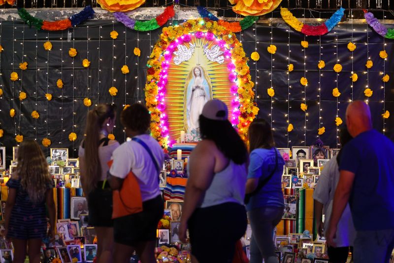 Attendees view photos of deceased people showcased on a large ofrenda at the 17th annual Día de los Muertos Festival in downtown Corpus Christi on Oct. 26, 2024.