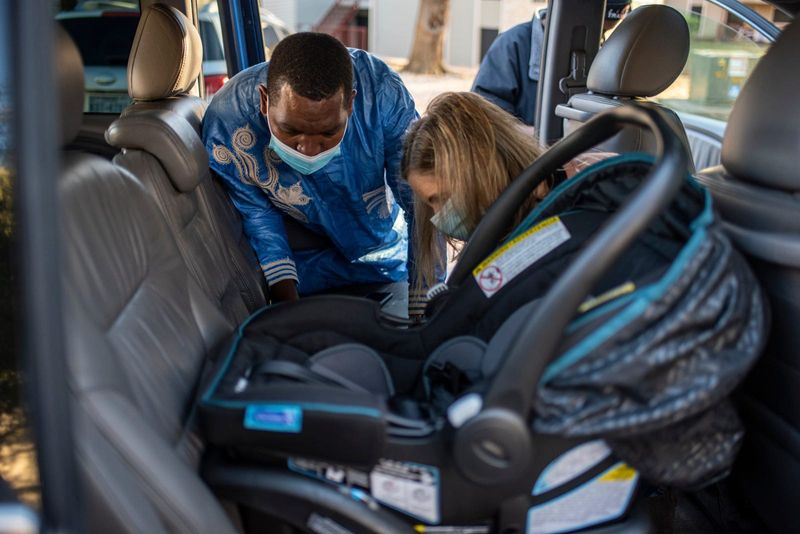 Paula Falk and Albert Byishimo try to install a car seat in 2020 as part of a Statesman Season for Caring car donation. Legally, all children younger than eight should be in a car seat, but in practicality, any child smaller than 4 foot 9 inches should be in either a car seat or a booster seat and should be in the back seat.